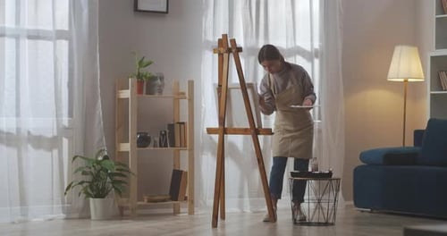 Woman Paints on Canvas in Cozy Apartment