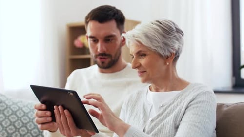 Man and Senior Woman Using a Tablet Together