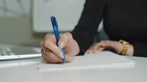 Female Hand Close Up Writing with a Blue Pen on a White Sheet