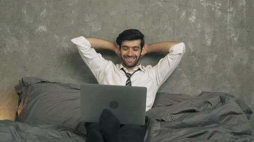 Smiling Man Working on Laptop While in Bed