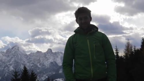 Silhouette of a man standing and looking at the scenic view of clouds and mountains in the winter.
