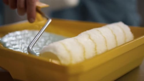 Man Hand Putting Paint Roller to Tray in New Apartment