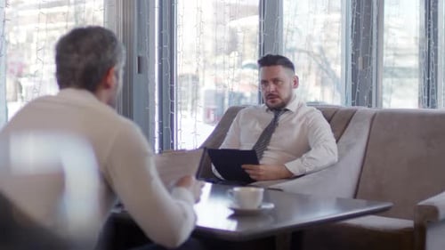 Two Men in Suits Discussing Business in Urban Cafe