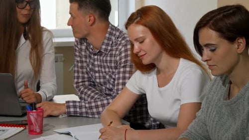 Young Adults Work Together at Table with Laptop