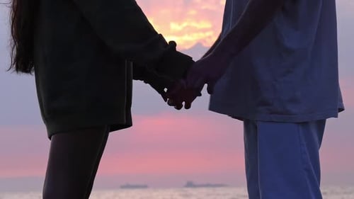 Couple Holding Hands at Sunset at the Beach