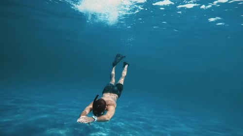 Un homme nage en apnée sous l'eau
