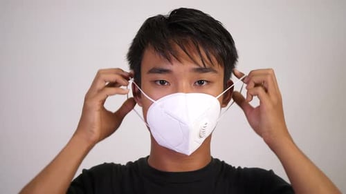 Young Adult Putting on a Protective Face Mask