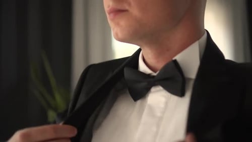 Man Puts on Black Suit Jacket with Bow Tie