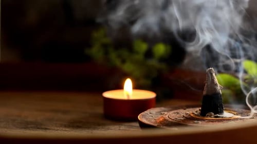 Incense cone and candles on tray with teapot