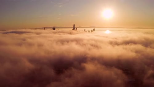 Aerial View of Cityscape Over Clouds at Sunrise