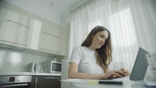 Woman Works on Laptop at Kitchen Table
