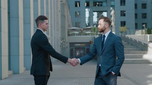 Businessmen in Suits Shake Hands in City