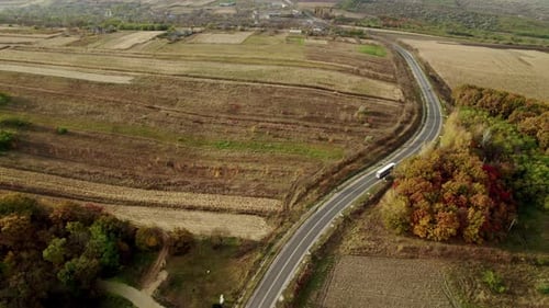 Straight Paved Road with a Truck Moving on a Beautiful Colorful Forest