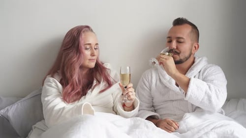 Couple Toasting Champagne in Bed Together