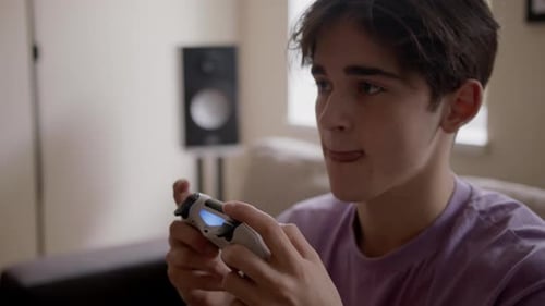 Young Man Playing Video Game with Controller Indoors