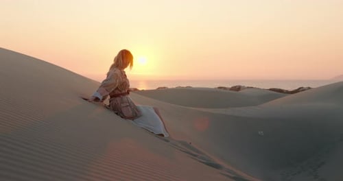 Woman Sits on Sand Dune Enjoying Sunset