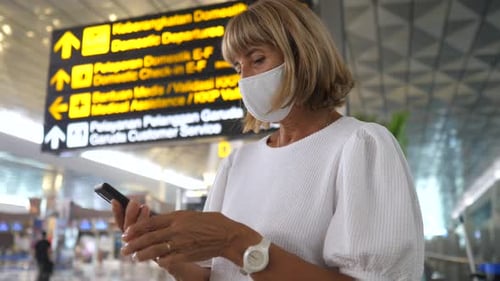 Woman in a Face Mask Checking Her Phone Before the Departure at the Airport