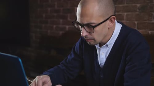 Handsome Mid-aged Man Sitting at Table in Office and Typing on Laptop While Working on Business