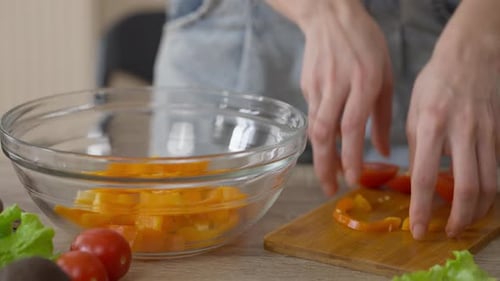 Weibliche Hände fügen Bio-Paprika und Tomate in transparenter Salatsch