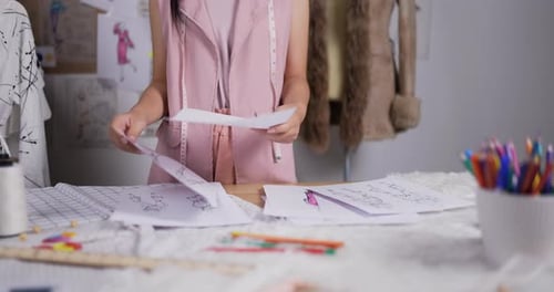 Fashion Designer Reviews Sketches in Her Studio