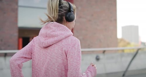 Sporty woman jogging and listening to music in the city