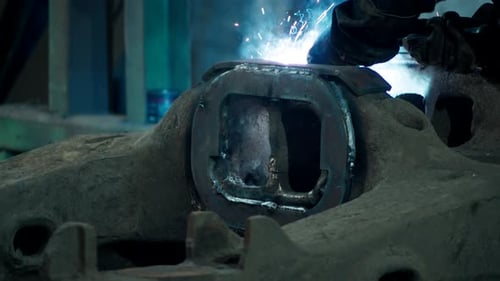 Worker Welding Large Metal Machinery in Factory