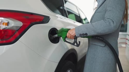 Woman Fills Petrol Into Her Car at a Gas Station
