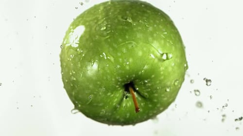 Fliegen des grünen Apfels in weißer Küche Hintergrund in Zeitlupe