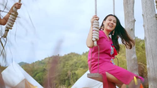 Women Enjoying Swings Outdoors on a Sunny Day