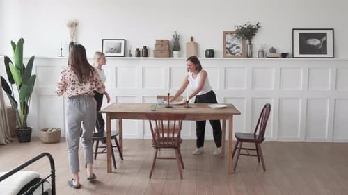 Young Women Arranging Table Setting in Bright Home