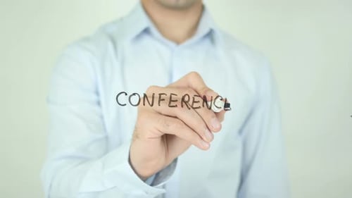 Man Writes Conference With Marker on Glass