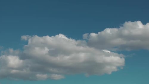 Langsam bewegen sich weiße Wolken und breiten sich am Himmel aus