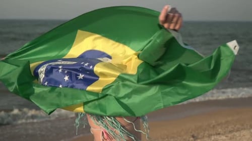 Woman Smiling and Holding Brazil Flag at Beach