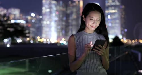 Woman Uses Smartphone in Urban Setting at Night
