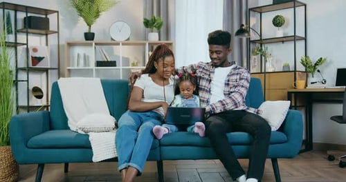 Pareja africana con hija usando una computadora portátil en casa