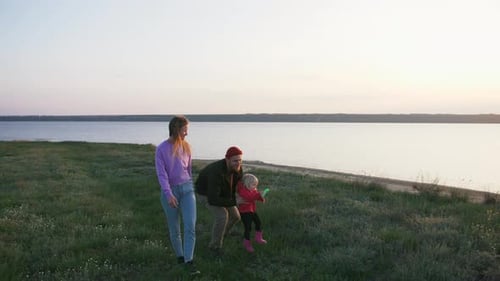Happy Family Walking with Flying Kite on Field Near Seashore During Sunset Slow Motion