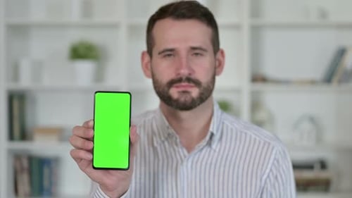 Young Adult Holding Phone with Green Screen Indoors