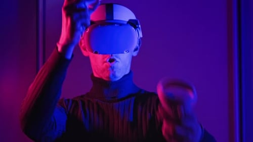 Man Uses VR Headset and Controllers in Dark Room