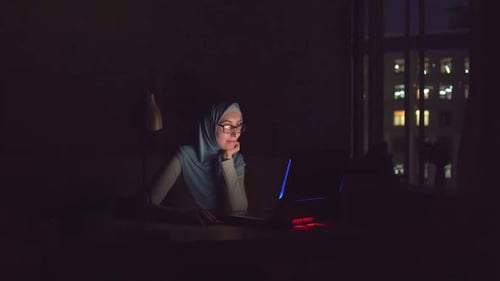 Woman Works on Laptop at Desk at Night