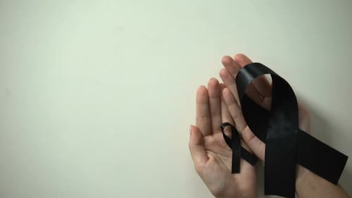 Big and Little Black Ribbons in Hands, Melanoma Awareness, Skin Cancer Treatment