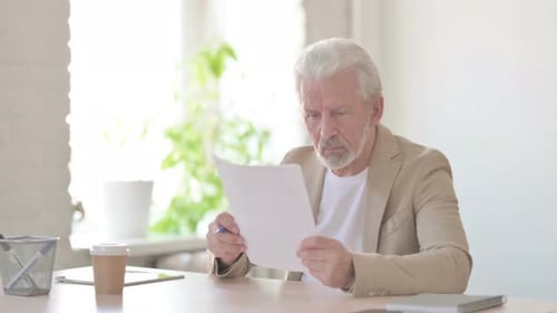 Senior Man Reviews Documents in Bright Office
