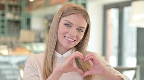 Smiling Woman Makes Heart Shape with Hands
