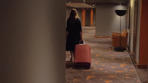 - Woman with Suitcase Walking To the Room in Hotel Corridor