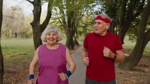 Active Senior Elderly Couple Doing Cardio Morning Exercise Workout. Man, Woman Running in City Park.