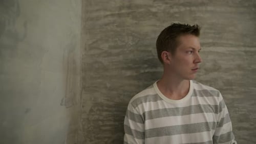 Young Man Stands By Gray Textured Wall