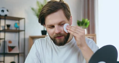 Man Cleansing Face with Cotton Pad