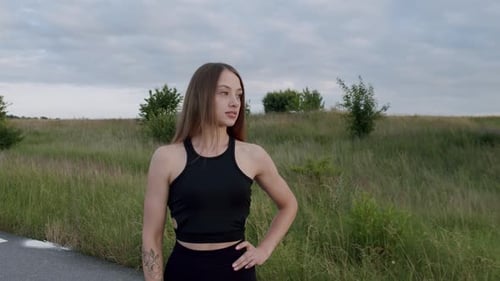 Portrait of Beautiful Athletic Girl Looking at Camera on the Road Among Nature