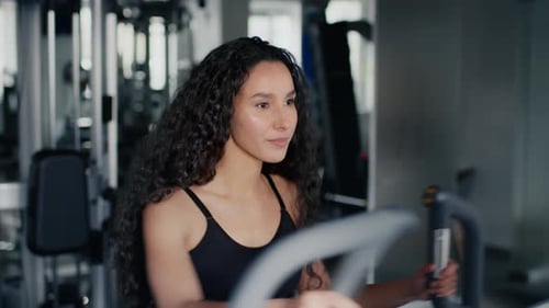 Woman Working Out on Elliptical Machine at Gym