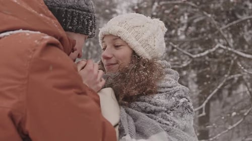 Affectionate Couple Warming Hands in Snowy Winter Forest