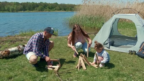 Family is Resting on the Bank of the River with a Tent